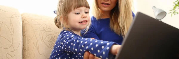 Linda niña en el sofá con el ordenador portátil de uso mamá —  Fotos de Stock