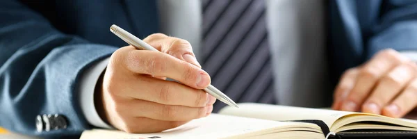 Male arm in suit and tie hold silver pen