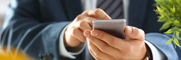 Male arm in suit hold phone and silver pen