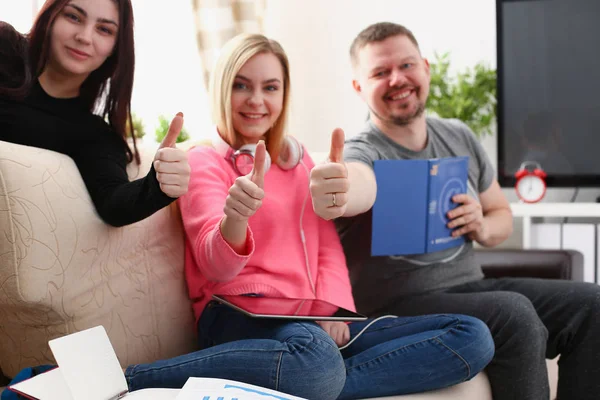 Група друзів проводять час разом сидячи на дивані у вітальні показують великий палець — стокове фото