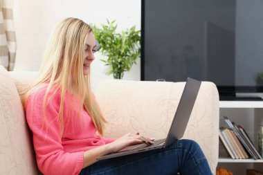 genç güzel sarışın kadın sit kanepe oturma tutun laptop kollarında