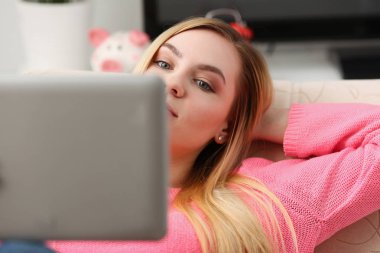 genç güzel sarışın kadın yalan kanepe oturma tutun tablet kollarında