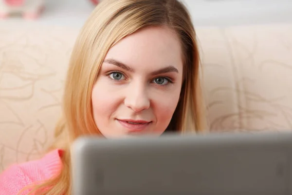 Young beautiful blond woman sit on the sofa in livingroom hold tablet in arms — Stock Photo, Image