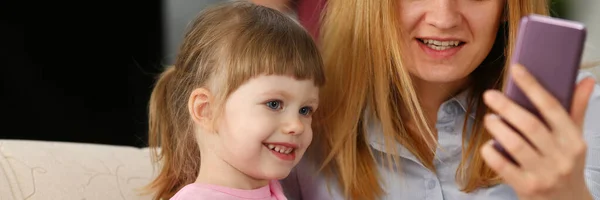 Moeder en haar baby meisje dochter met behulp van mobiele telefoon voor het bellen van broers en zussen — Stockfoto