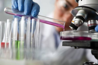Kadın kimyagerin elinde cam test tüpü var.