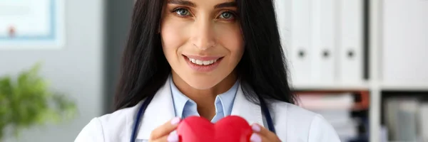 Beautiful smiling GP holding in hands red toy heart — Stock Photo, Image