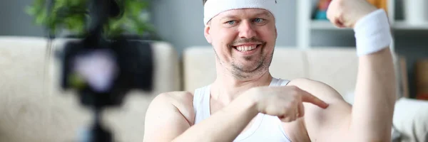 Hombre sonriente mostrando bíceps y músculos en las manos — Foto de Stock