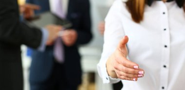 Businesswoman in suit and tie offering hand to shake to visitor