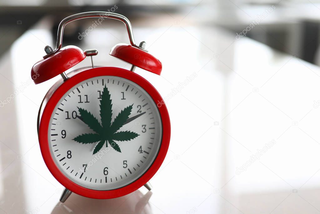 Red alarm clock with marijuana logo on office table