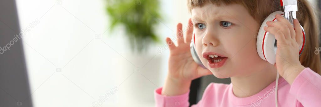 Little girl wearing headphones using computer aggressive articulating