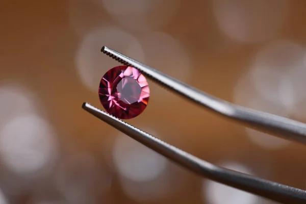 Jeweler in workshop holds pink stone in tweezers — Stock Photo, Image