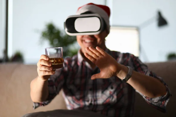 Mann sitzt auf Sofa und hält Glas in der Hand und benutzt Vr-Brille — Stockfoto