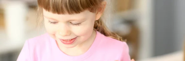 Lächelndes kleines Mädchen, das beim Spielen etwas Interessantes tut — Stockfoto