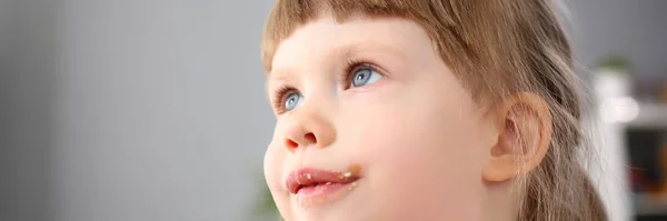 Menina comendo doces de chocolate doce com traço em sua boca — Fotografia de Stock