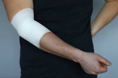 Dar, elastik bandajlı erkek eli dirsek hizasında.