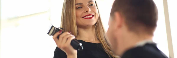 Peluquería sonriente usando maquinilla de afeitar eléctrica al cliente —  Fotos de Stock