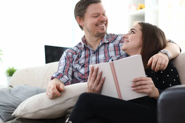 Glada par läser bok på soffan — Stockfoto