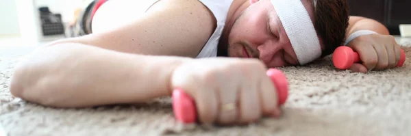 Erschöpfter Mann lag mit Hantel in der Hand auf dem Boden — Stockfoto