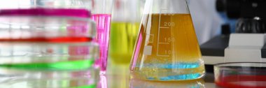 Mavi koruyucu eldivenli kadın kimyagerin elinde test tüpü var.