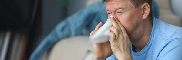 Man blaast zijn neus in een servet terwijl hij zit — Stockfoto