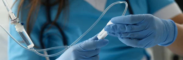 Vrouwelijke verpleegkundige hand in blauwe beschermende handschoenen houden druppelaar — Stockfoto