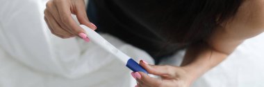 Hamilelik testi sonuçlarını elinde tutan kadın