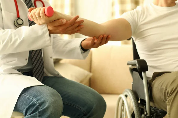 Male doctor helps lift dumbbell to disabled patient rehabilitation therapy concept. — Stock Photo, Image