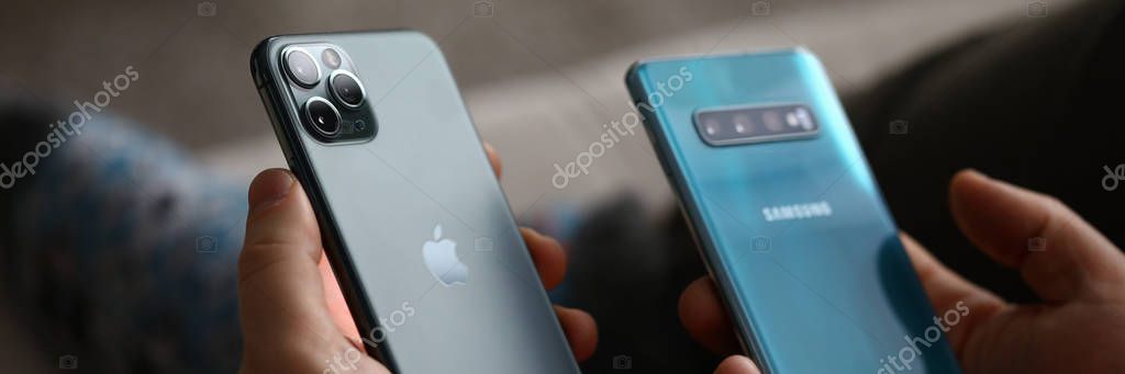 Minsk, Belarus - 11 December 2019 : Male hand hold Apple iphone pro and samsung galaxy s 10. Illustrative editorial
