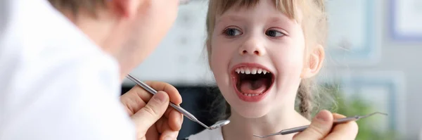Férfi fogorvos nézd meg a nyitott szájú litle boldog lány — Stock Fotó