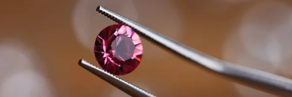 Smycken i verkstad håller rosa sten i pincett — Stockfoto