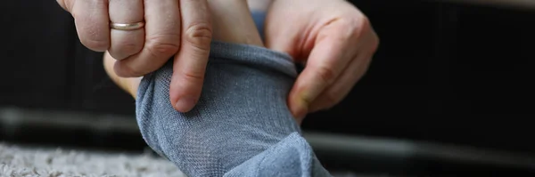 El hombre en casa por la mañana se pone calcetines grises en la pierna —  Fotos de Stock