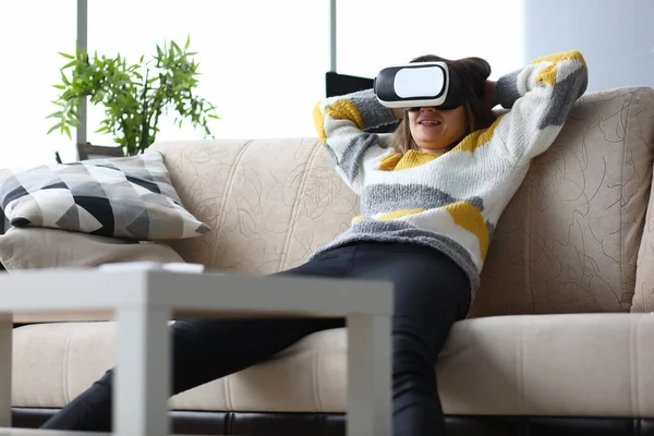 Menina senta-se sofá casa relaxa com óculos virtuais — Fotografia de Stock