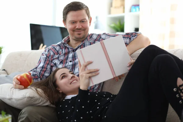Couple reading book together at home on couch — Stockfoto