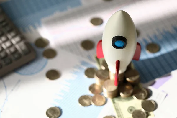 Toy space rocket stands on coins near calculator — Stockfoto