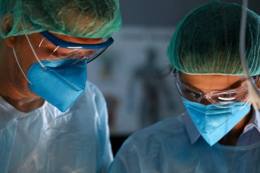 Surgeon and anastasiologist in uniform look down