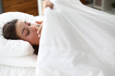 Girl woke up and looks in surprise under blanket