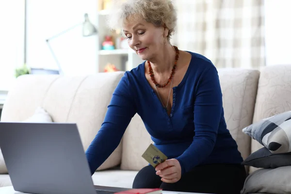 Woman holding credit card while sitting laptop