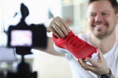 Man holds sneaker in front video camera, overview
