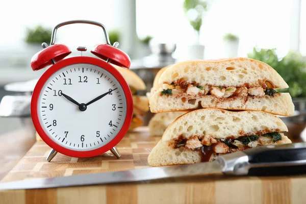Red alarm clock with sandwich stands on wooden table background — Stock Fotó