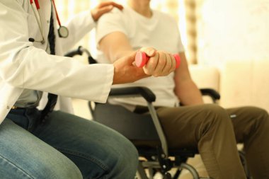 Handicapped man sits working out dumbbell arm
