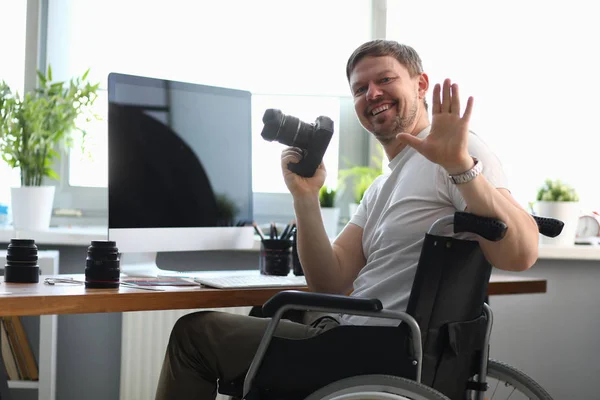 Чоловік-фотограф сидить на інвалідному візку за столом — стокове фото