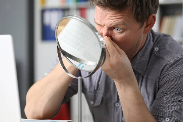 Man sits in front mirror and presses on his face — Stockfoto