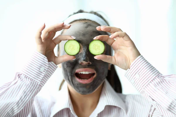 Girl with mask on her face shows slices cucumbers — Stock Fotó