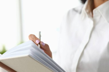 Yakın plan kadın defterdeki kalemle notlar alıyor.