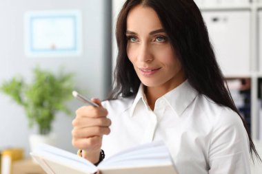 Attractive girl makes diary entries shows with pen