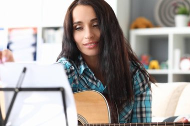 Müzisyen, müzik sehpasında gitar notasına bakar