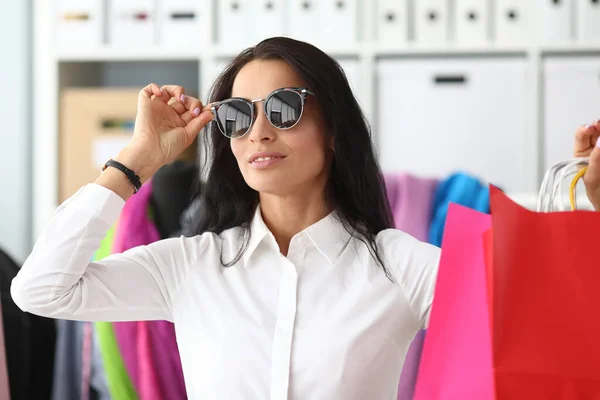 Стильная девушка надевает солнцезащитные очки в магазине одежды — стоковое фото