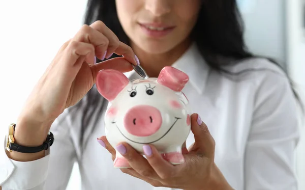Miła dziewczyna umieszcza monetę w ceramicznej figurce świni — Zdjęcie stockowe