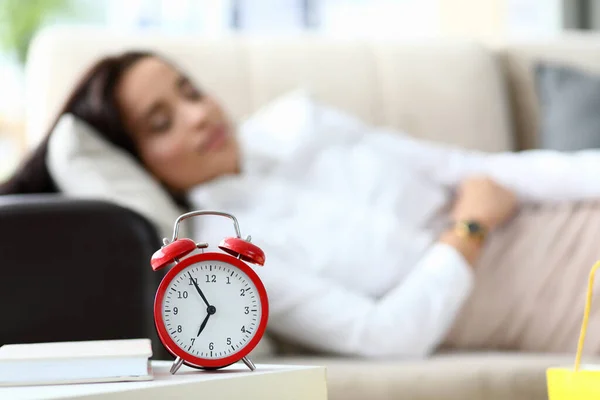 Girl is tired and lies on table an alarm clock — Stock Photo, Image