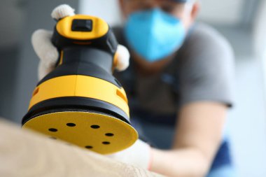 Sarı öğütücü elinde disk zımpara makinesiyle elinde tutan bir erkek.